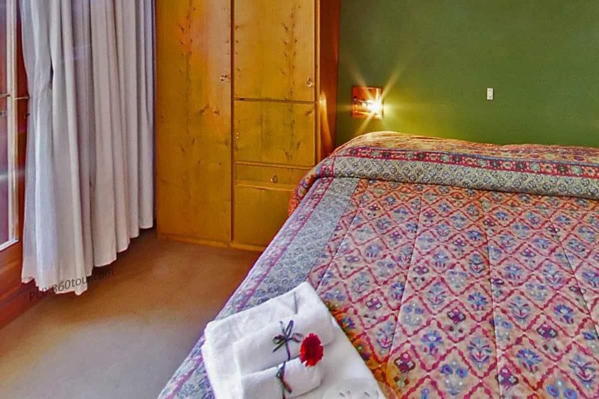 Une chambre à coucher avec un lit, une fenêtre avec des rideaux et une armoire en bois.