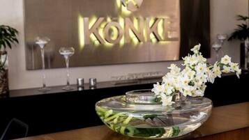 A reception area with a glass bowl containing white flowers and a gold sign with the text "KONKE".