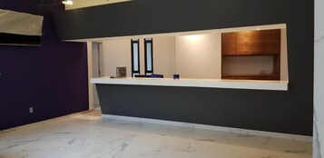 Un área de recepción con una pared oscura, una barra blanca y un mueble de madera.