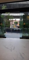 Une entrée en verre donnant sur un immeuble et des voitures garées.