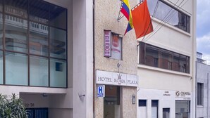 Un immeuble avec une enseigne indiquant « Hôtel Roma Plaza » et un magasin « Colpatria ».