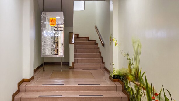 Un escalier agrémenté d’une pancarte de bienvenue, d’une main courante et de plantes en pot.