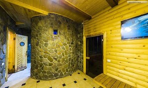 L’intérieur d’un chalet en bois, avec un mur en pierre, une porte en bois et un tableau encadré accroché au mur.