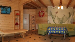 A wooden cabin interior with a dining table, a sofa, a bench, and a wall with a painting and a life preserver. - Laguna Hotel (Slavske)