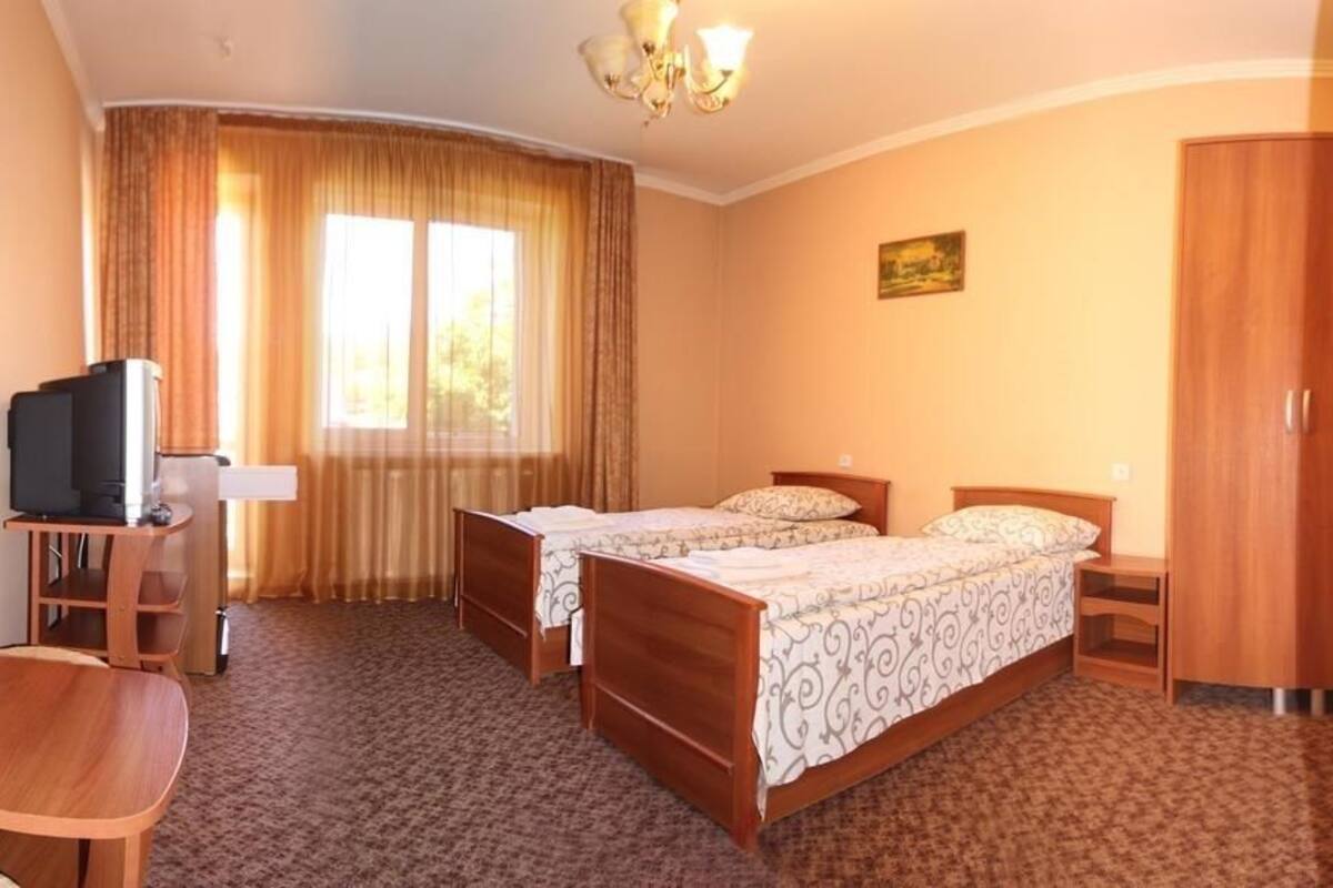 A hotel room with two beds, a desk, a television, and a wardrobe.