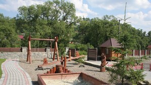 A rustic outdoor area with a wooden seesaw, a wooden bench, and a small wooden structure. - Laguna Hotel (Slavske)