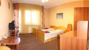 Une chambre d’hôtel équipée d’un lit, d’un bureau, d’une chaise, d’une télévision et d’une fenêtre avec des rideaux.