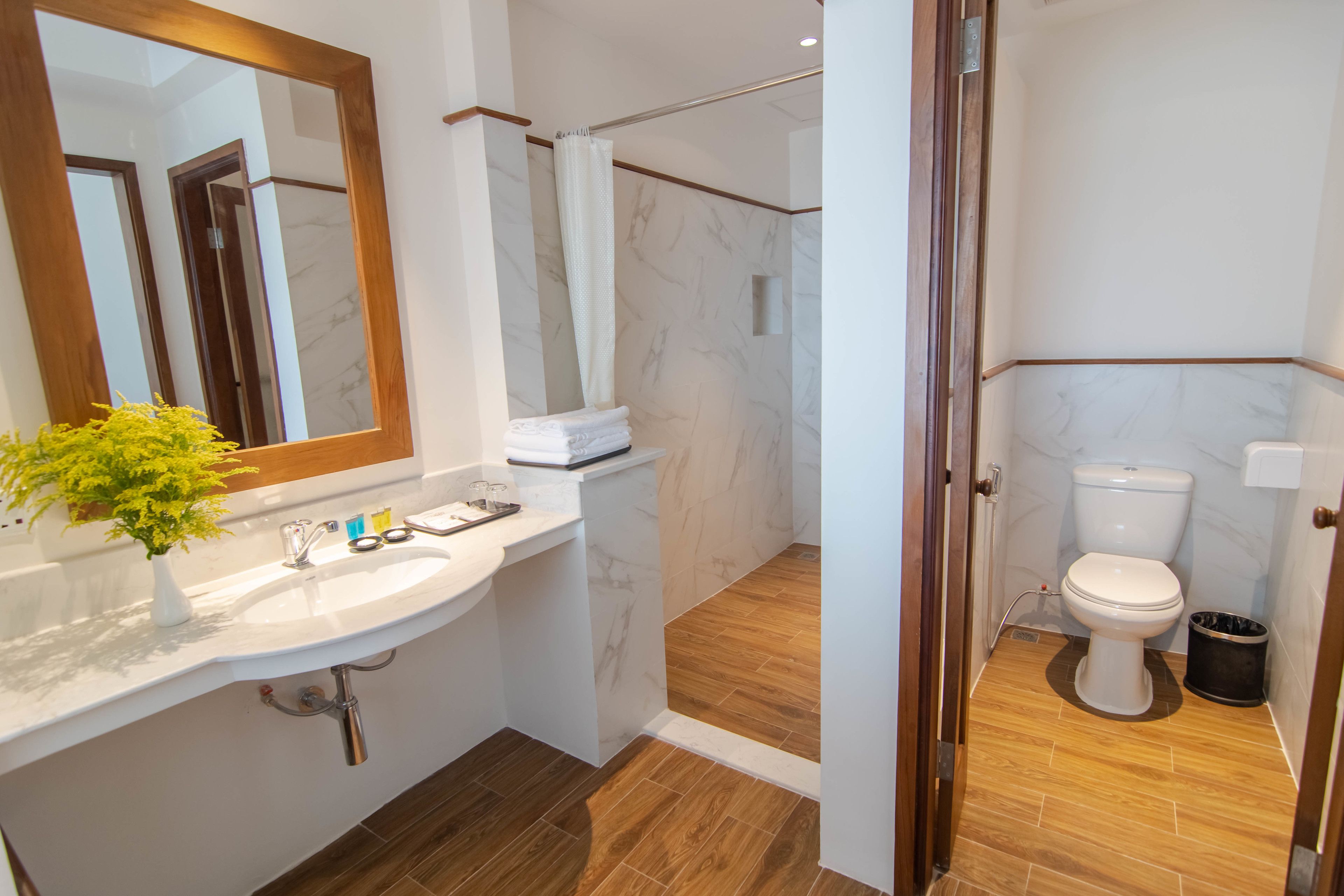 Un baño moderno con lavamanos de mármol, ducha e inodoro.