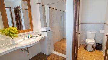 Un baño moderno con lavamanos de mármol, ducha e inodoro.