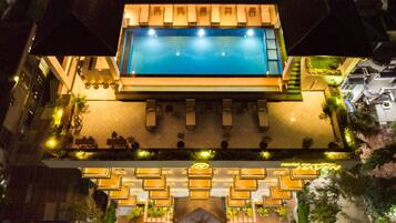 Un hotel con piscina en la azotea, asientos exteriores y una entrada bien iluminada.