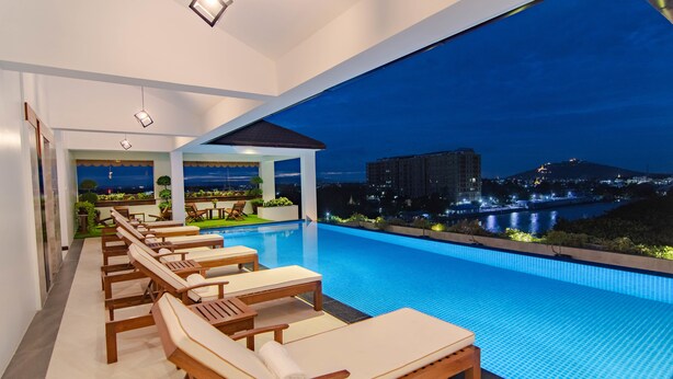 Una piscina interior moderna con sillones de descanso y vista a un paisaje urbano nocturno.