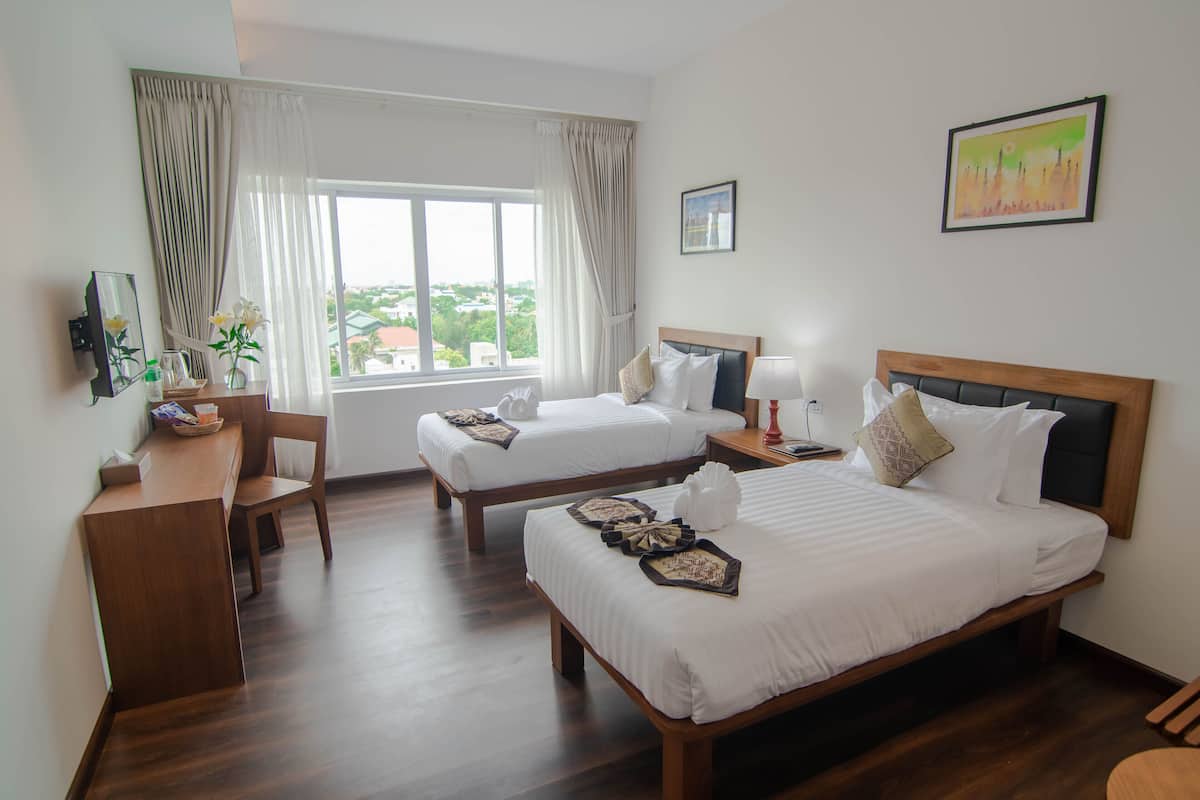 A hotel room with two beds, a desk, and a chair.