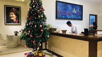 Een receptie met een kerstboom, kunstwerken in lijsten en een receptiebeambte.