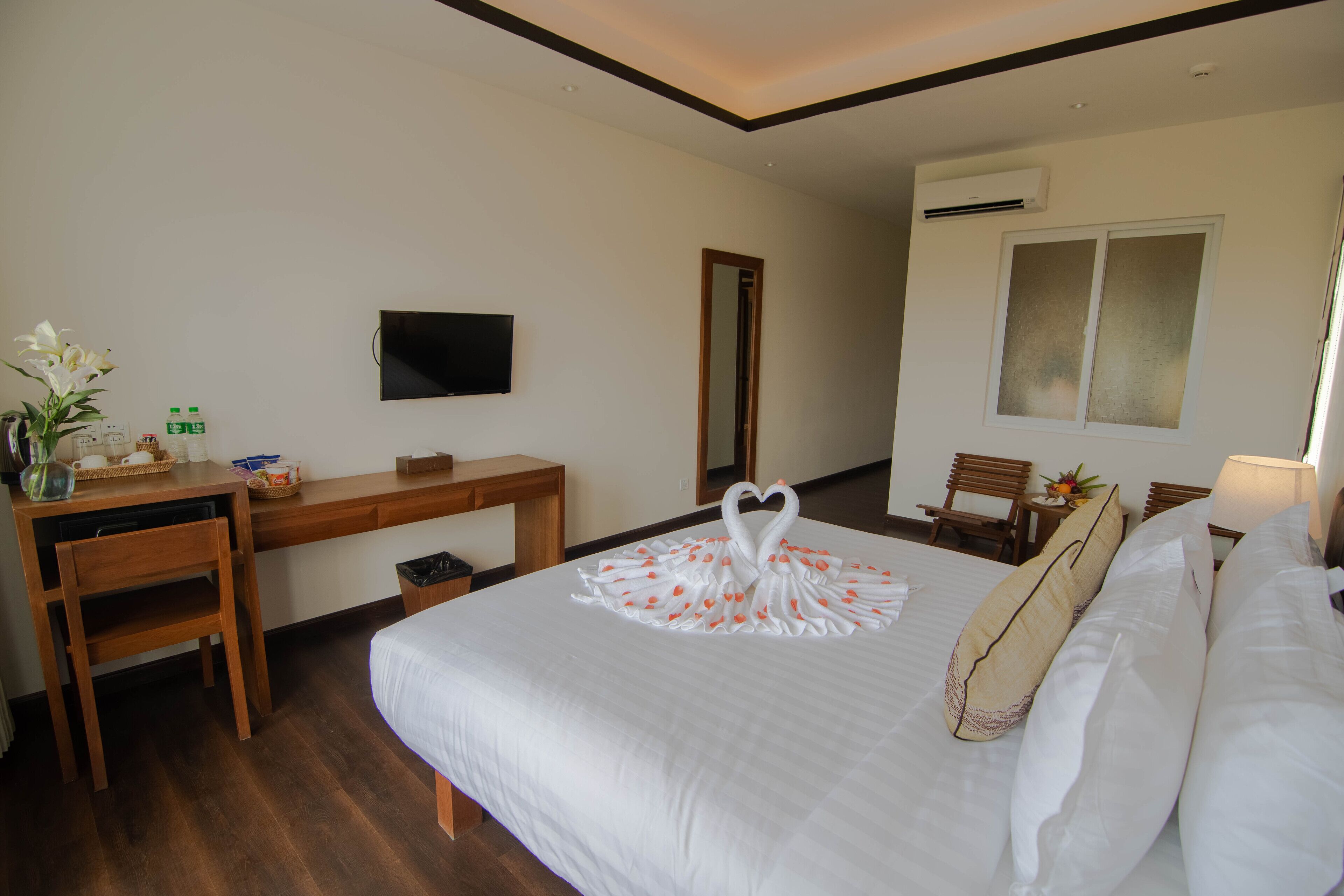 A hotel room with a bed, a desk, a chair, a TV, and a window.
