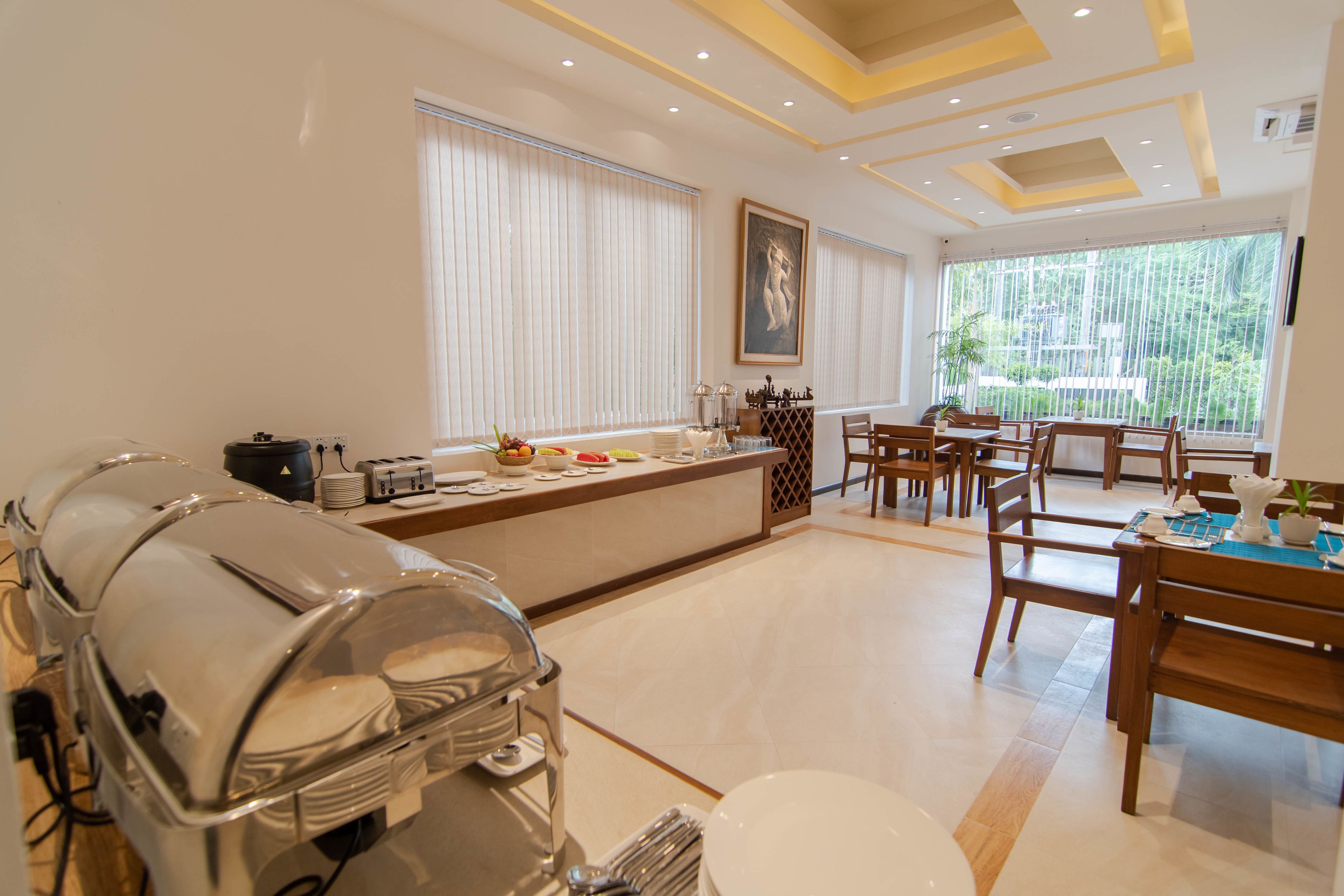 Cocina moderna con una mesa de buffet, comedor con sillas de madera y ventanas amplias con persianas.
