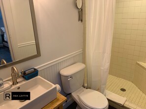 Een badkamer met een wit wastafel, toilet en douchegedeelte.