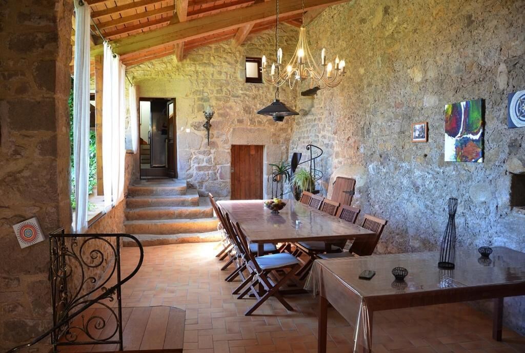 Un coin repas rustique avec un mur en pierre, un plafond en bois et un lustre.