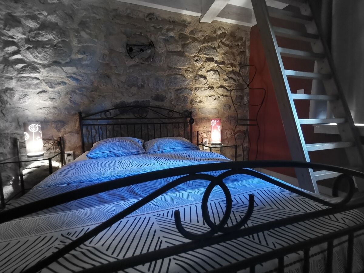 Ein Schlafzimmer mit einer Steinsandsteinwand, einem Metallbettgestell und einer roten Leiter.
