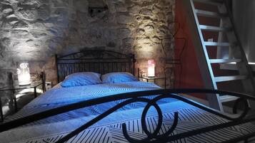Ein Schlafzimmer mit einer Steinsandsteinwand, einem Metallbettgestell und einer roten Leiter.