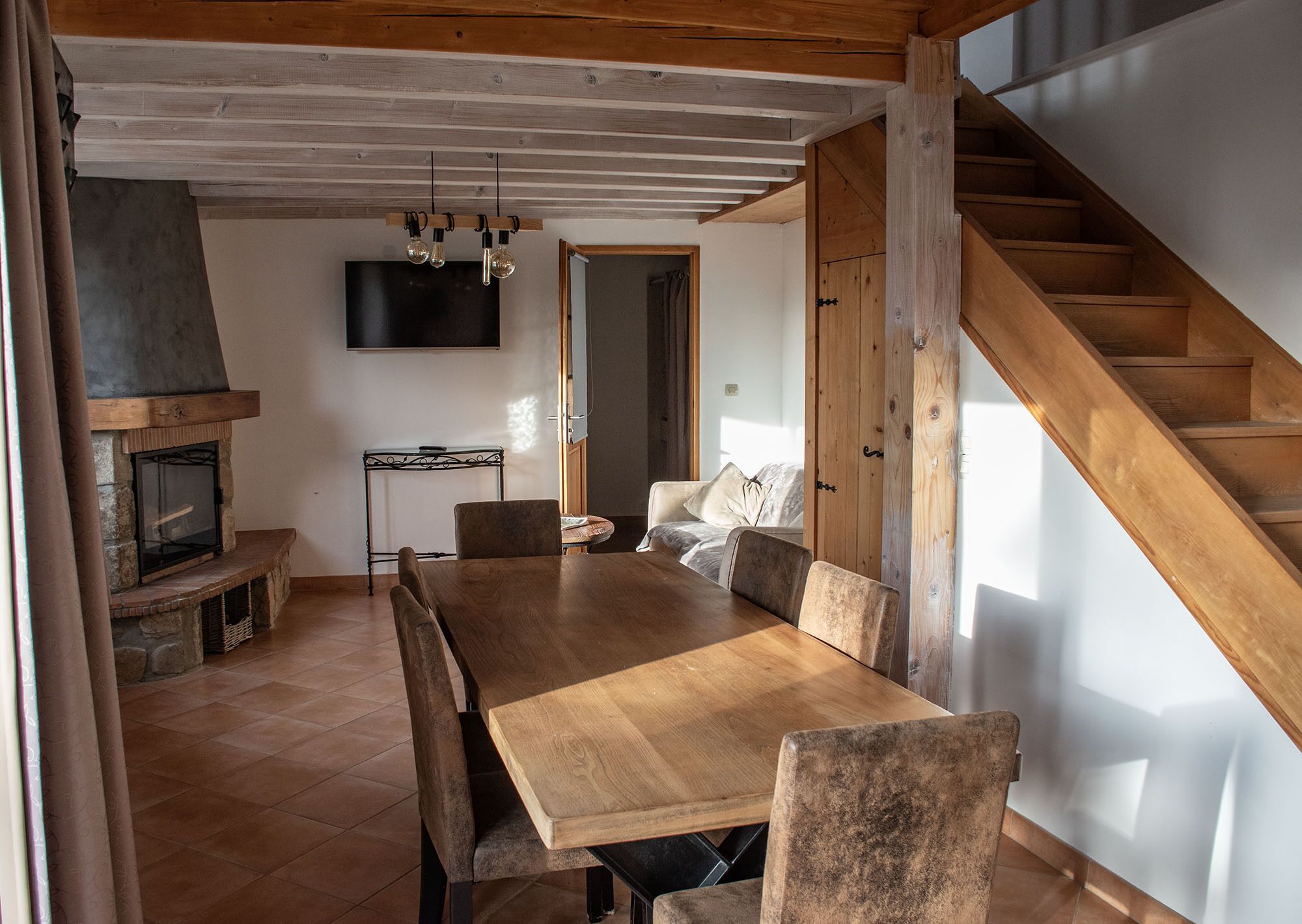 Un comedor amplio con una mesa y sillas de madera, una chimenea y un televisor instalado en la pared.