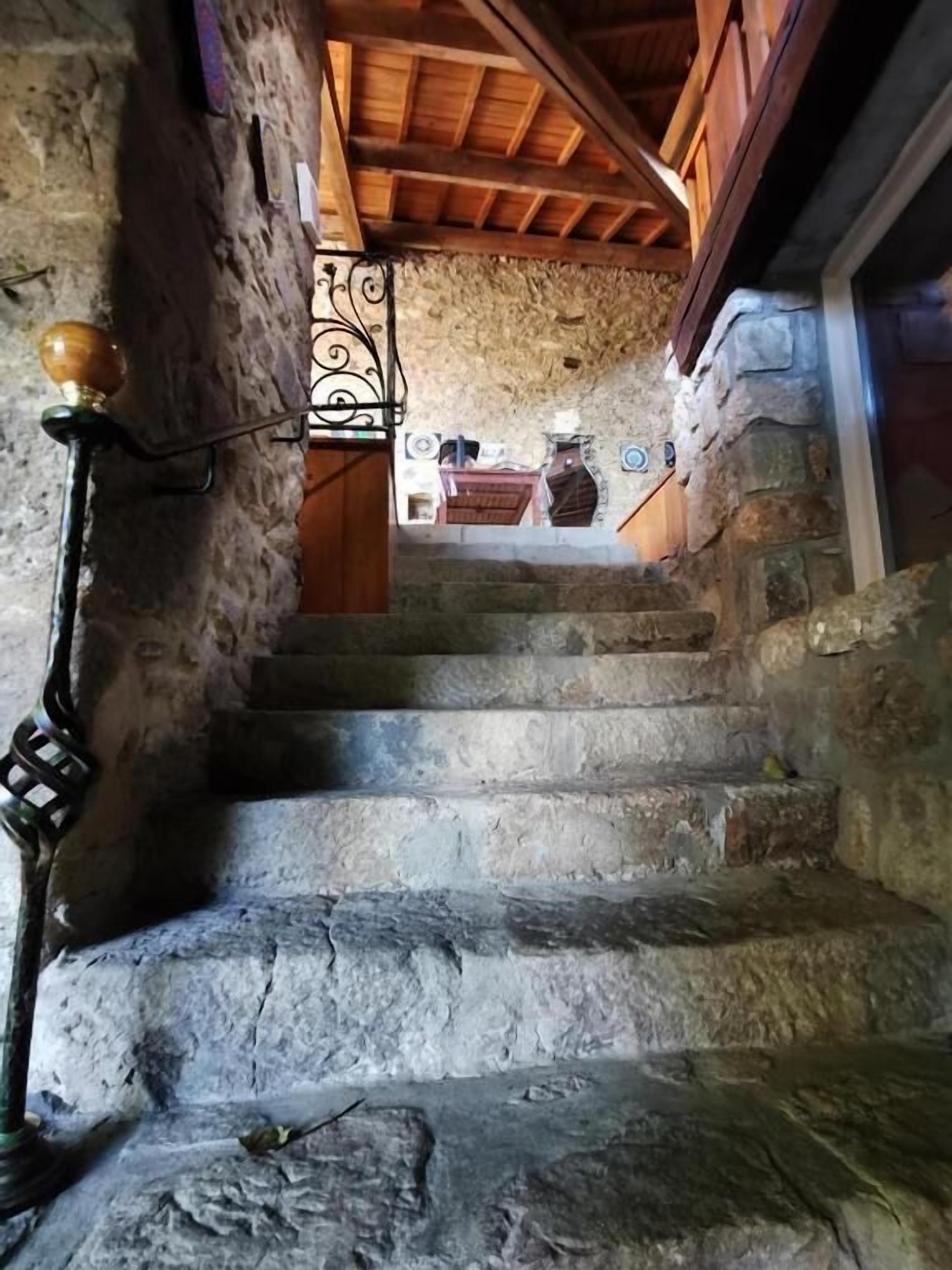 Eine Steintreppe führt zu einem Raum mit Holzboden und einer dekorativen Wandverkleidung.