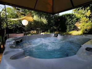 Un jacuzzi con toldo, rodeado de vegetación.