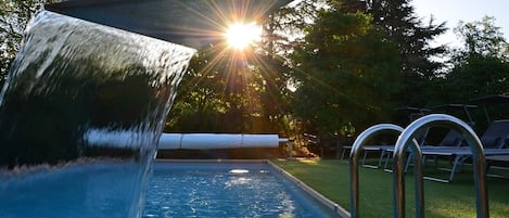 Una piscina al aire libre de temporada, sillones reclinables de piscina