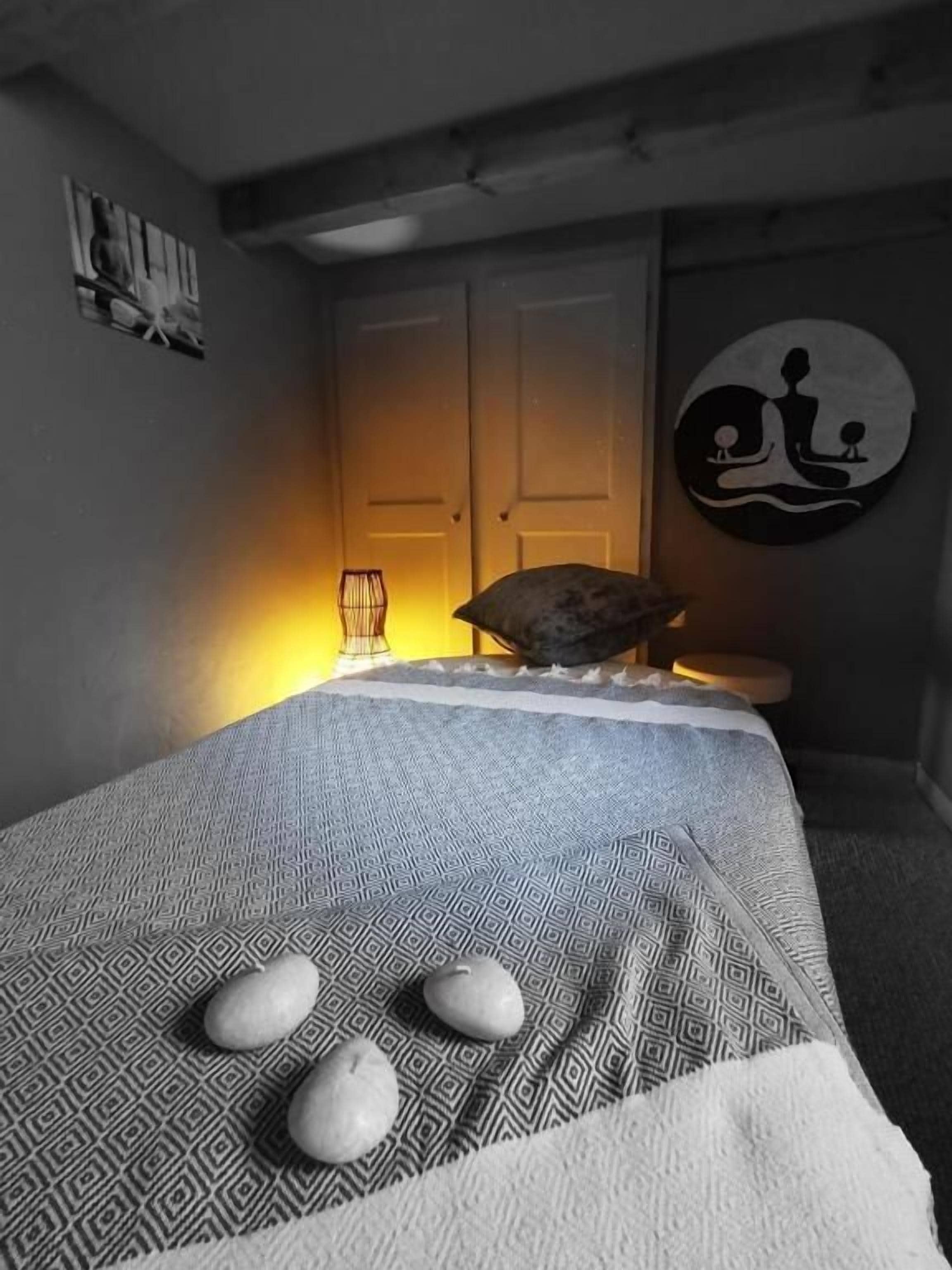 Une pièce avec un lit, une œuvre d’art accrochée au mur et une porte.