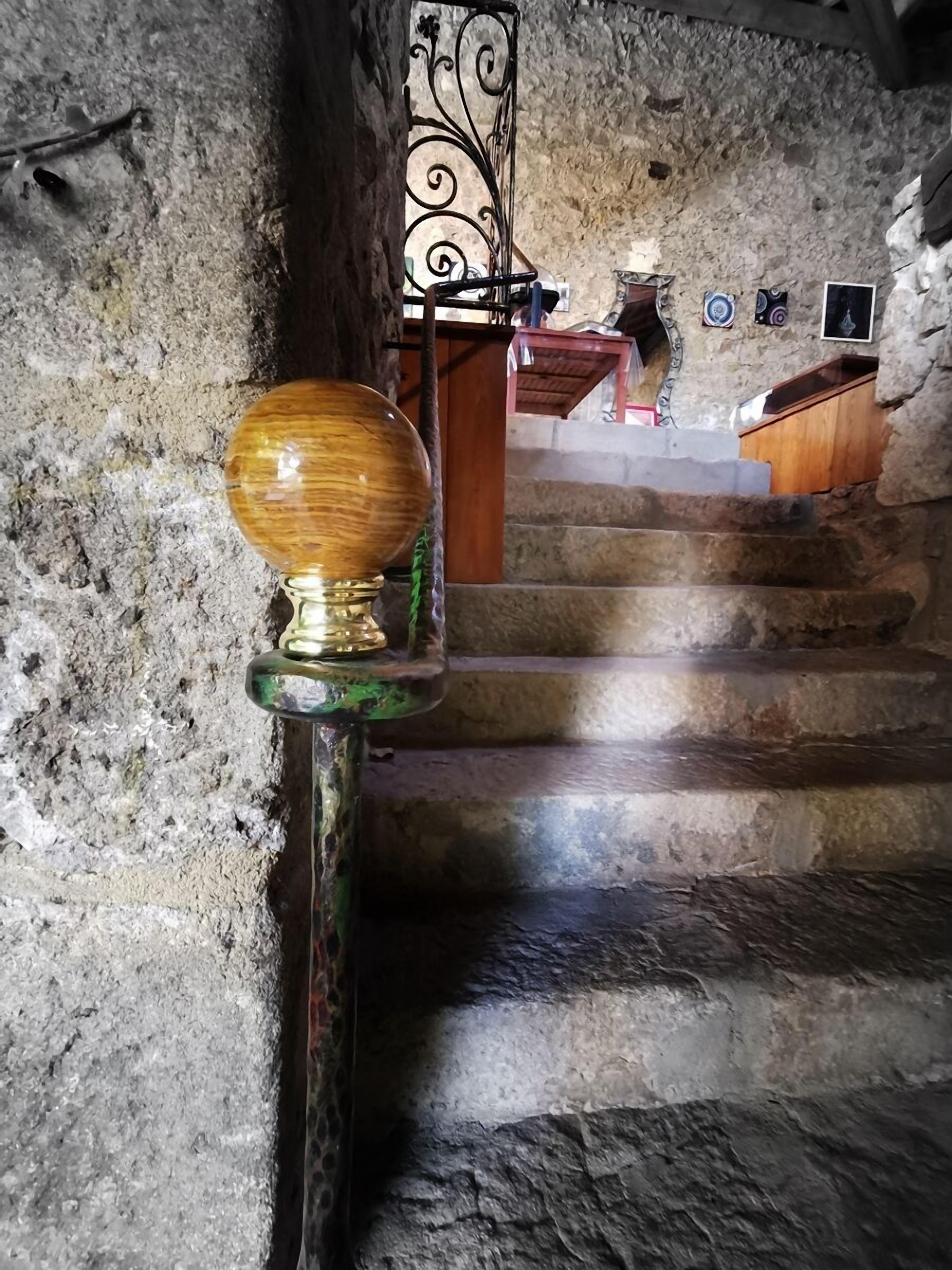A stone staircase with a wooden handrail and a metal balustrade.