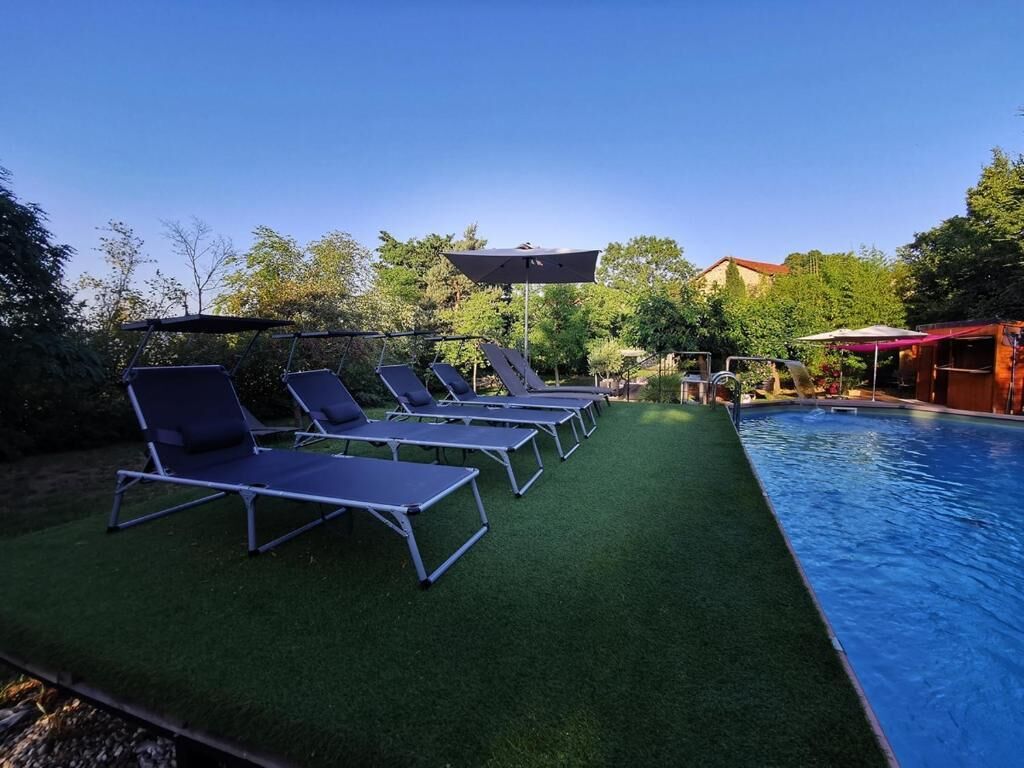 A swimming pool area with artificial grass and lounge chairs.