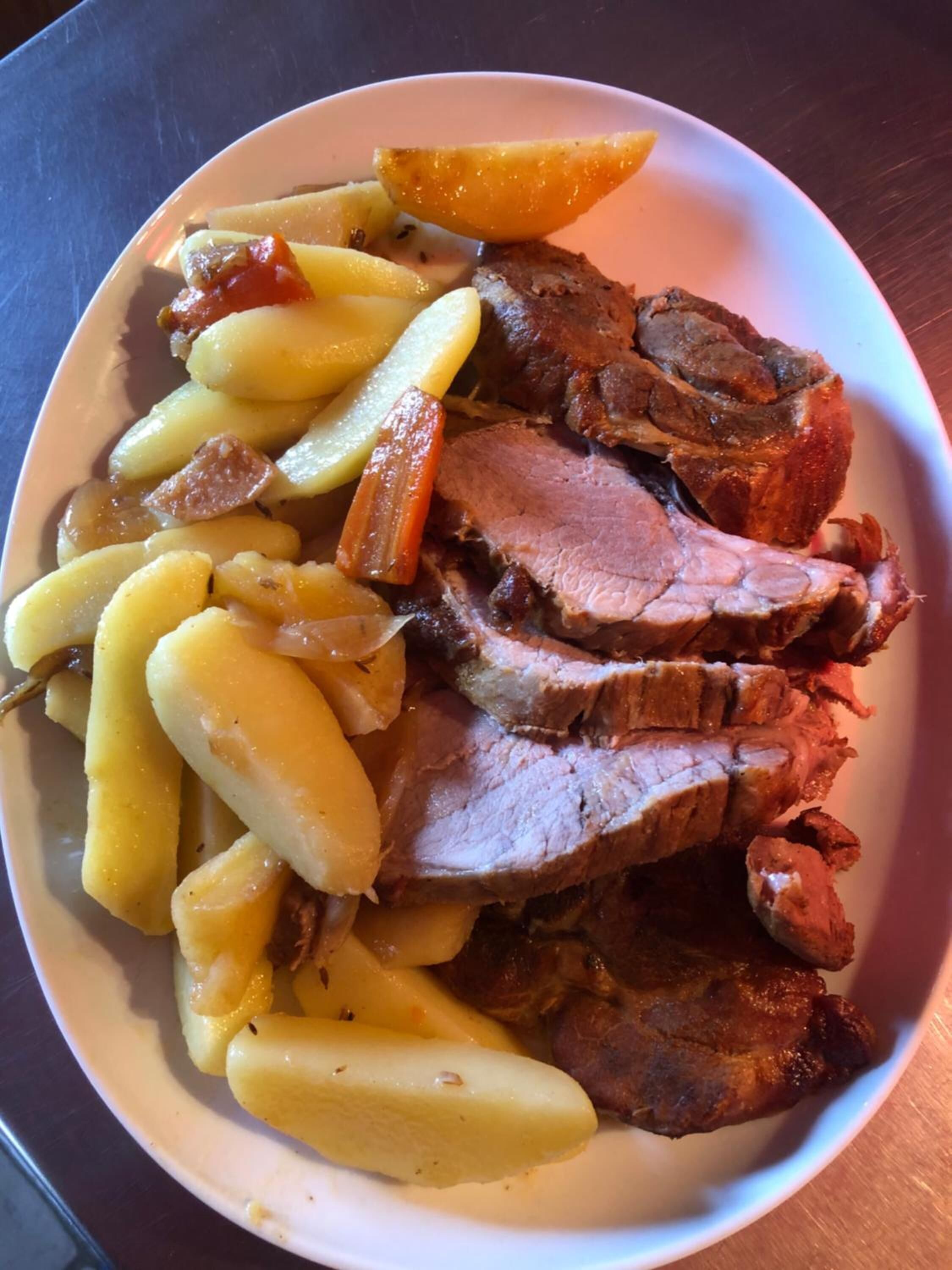 A plate of sliced roast beef with potatoes and carrots.