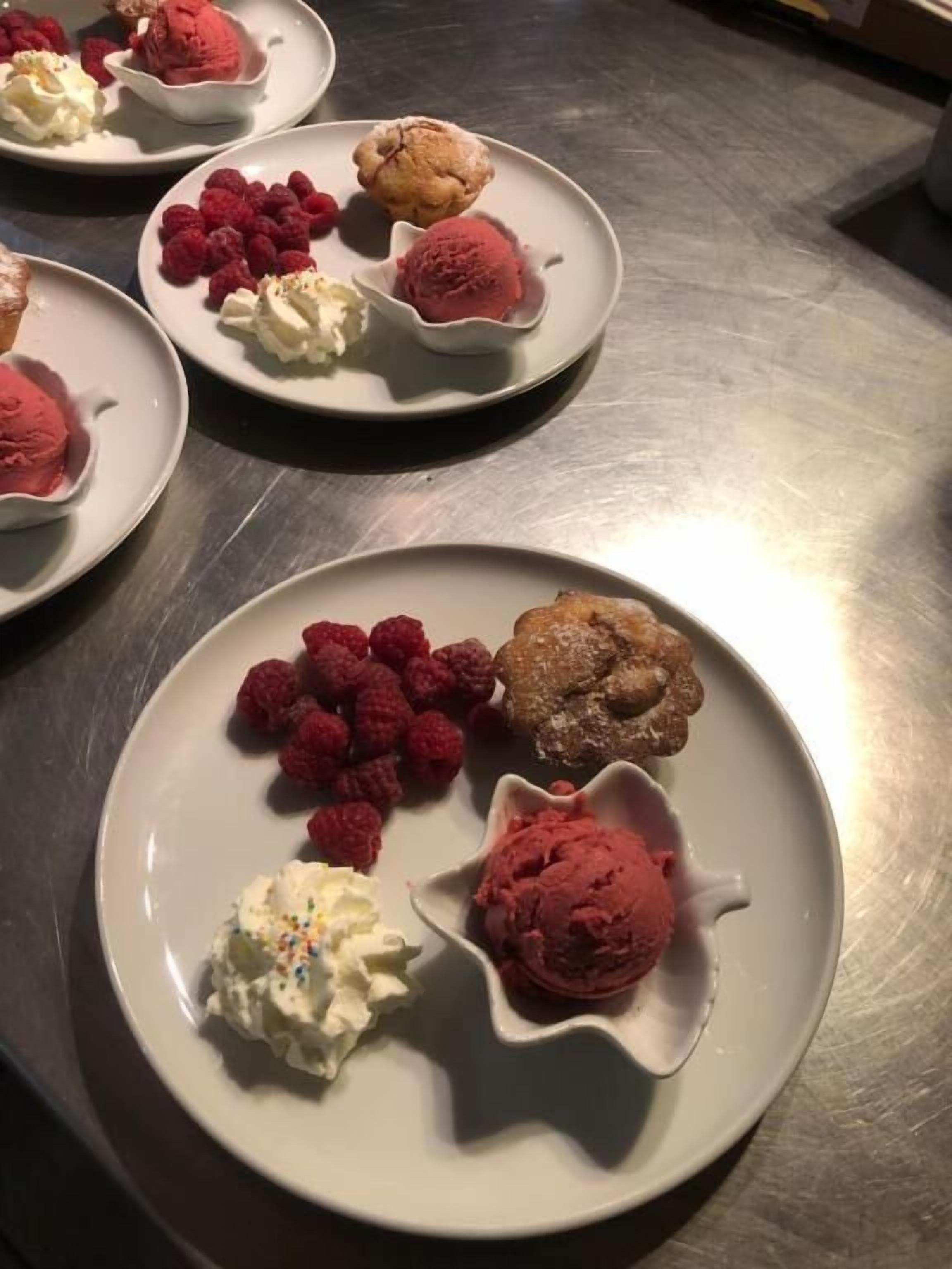 Een tafel van roestvrij staal met borden vol desserts, waaronder ijs en gebak.