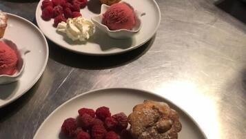 Een tafel van roestvrij staal met borden vol desserts, waaronder ijs en gebak.