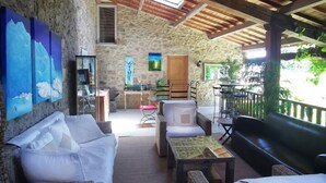 Un espace extérieur accueillant, aménagé avec des meubles en osier, un mur en pierre et un plafond en bois.