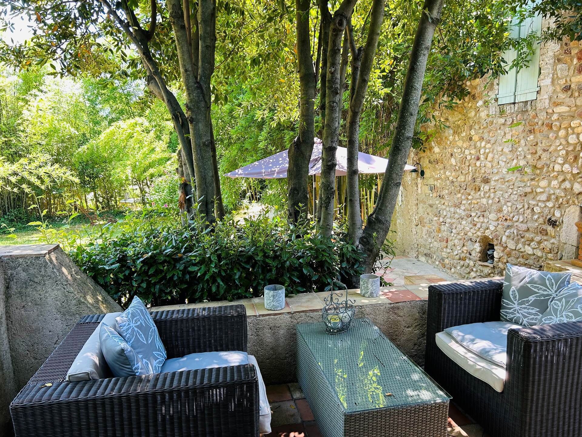 An outdoor seating area with wicker furniture and a stone wall backdrop.