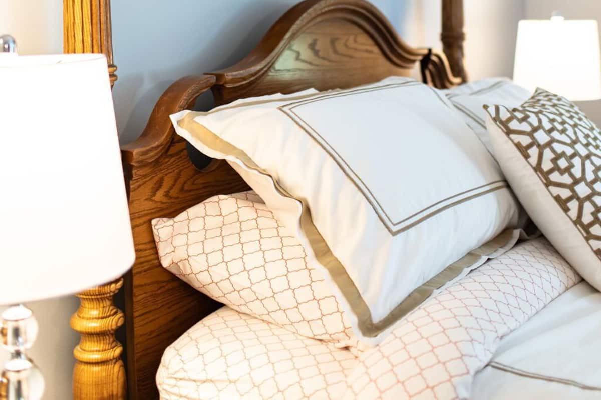Un dormitorio con estructura de cama de madera, un cuadro floral en la pared y una lámpara de noche.