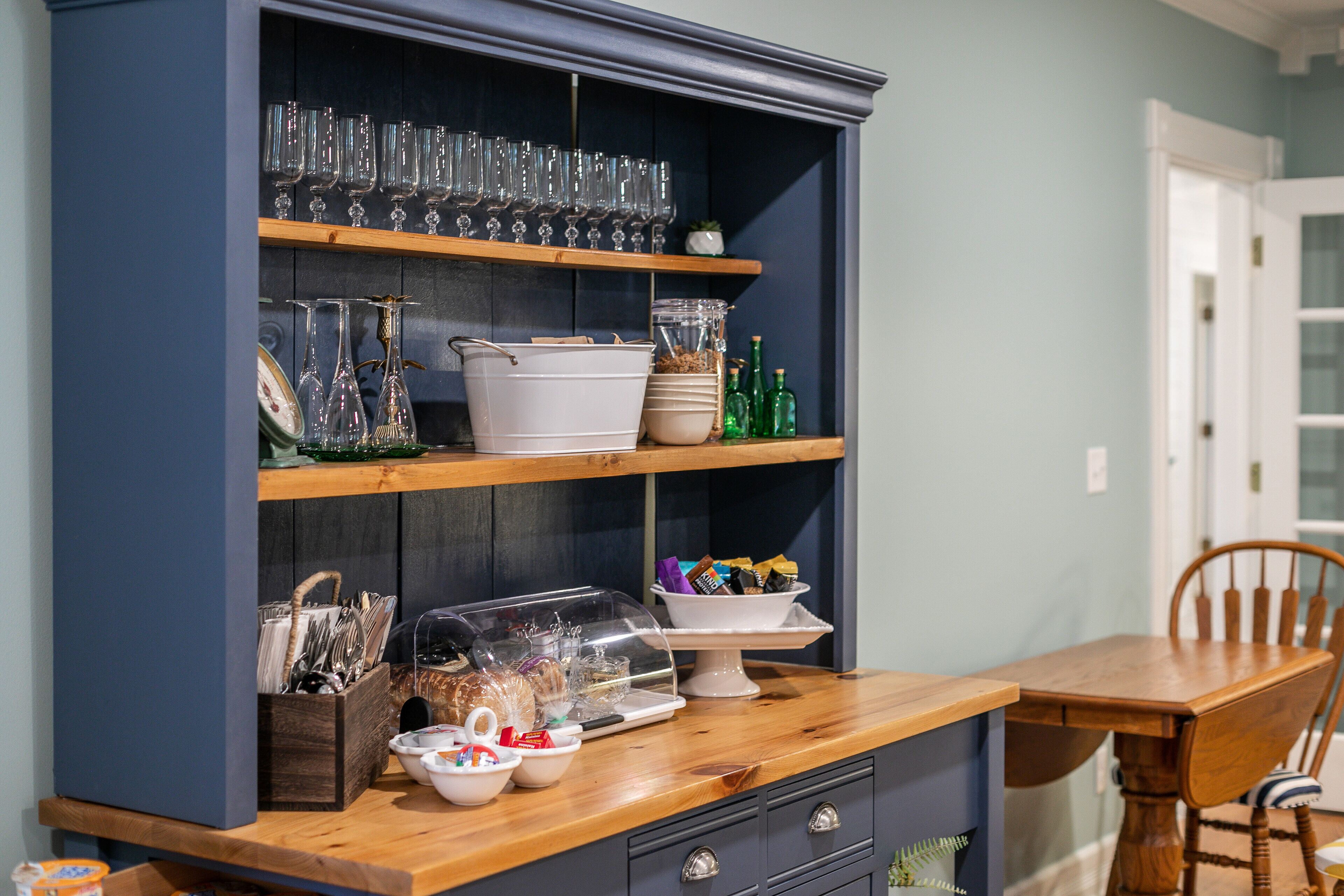 Una cocina con estantes de madera, una mesa de madera y una silla.