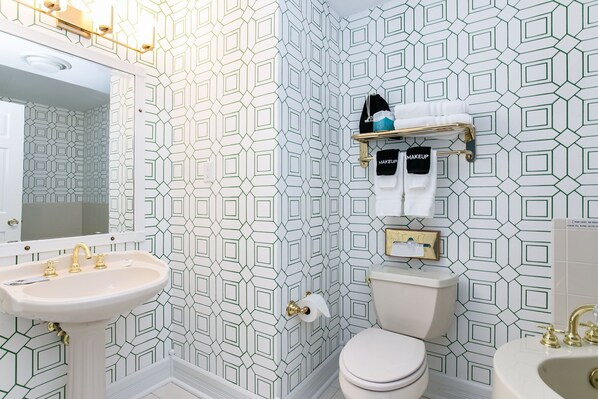 Une salle de bain avec un lavabo blanc, des toilettes et un miroir.
