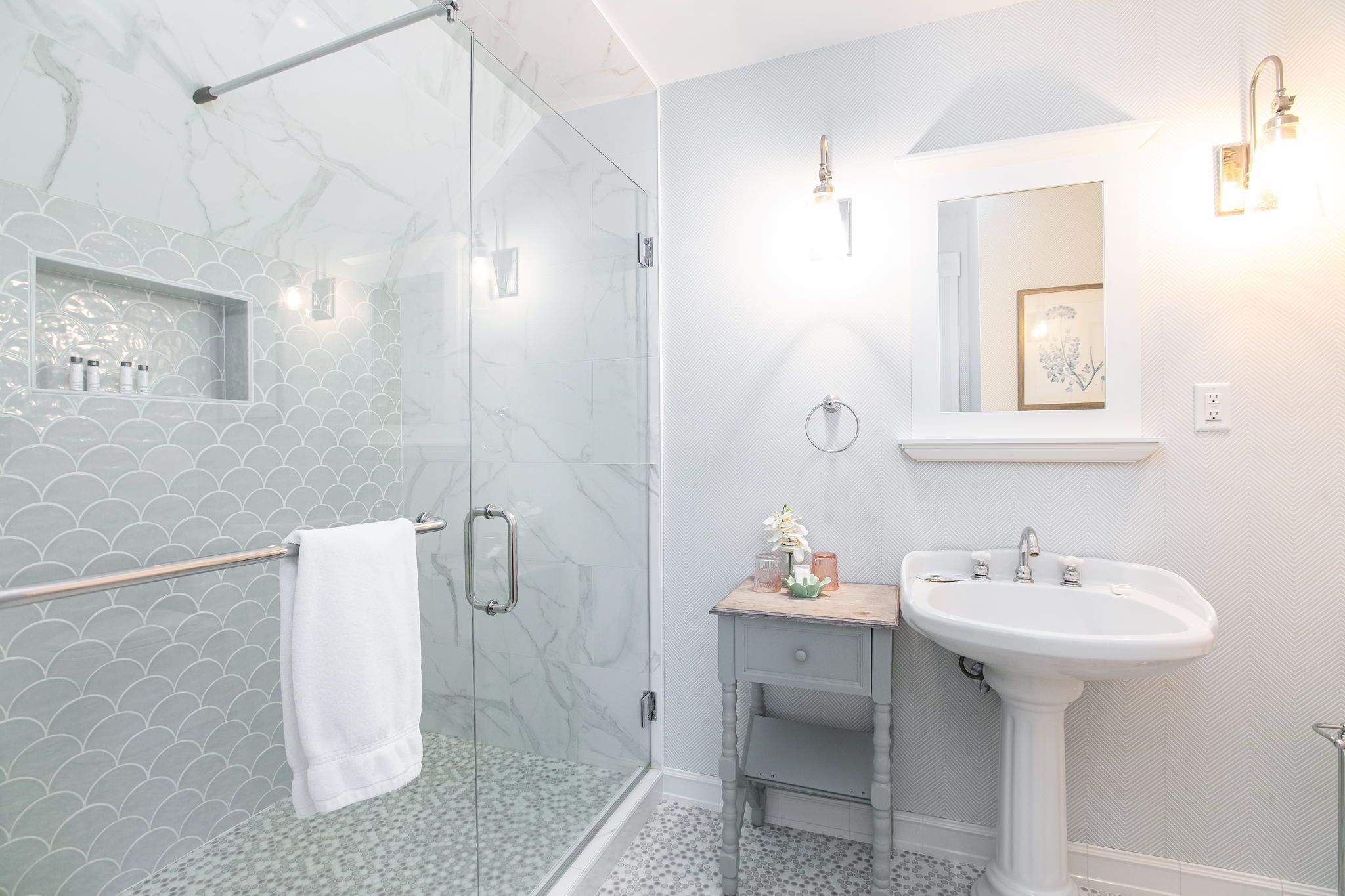 A modern bathroom with a glass shower enclosure, a vanity with a sink, and a mirror above the sink.