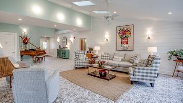 A spacious living room with a piano, two armchairs, a sofa, and a coffee table.