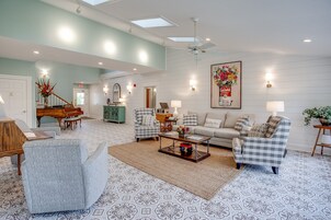 A spacious living room with a piano, two armchairs, a sofa, and a coffee table.