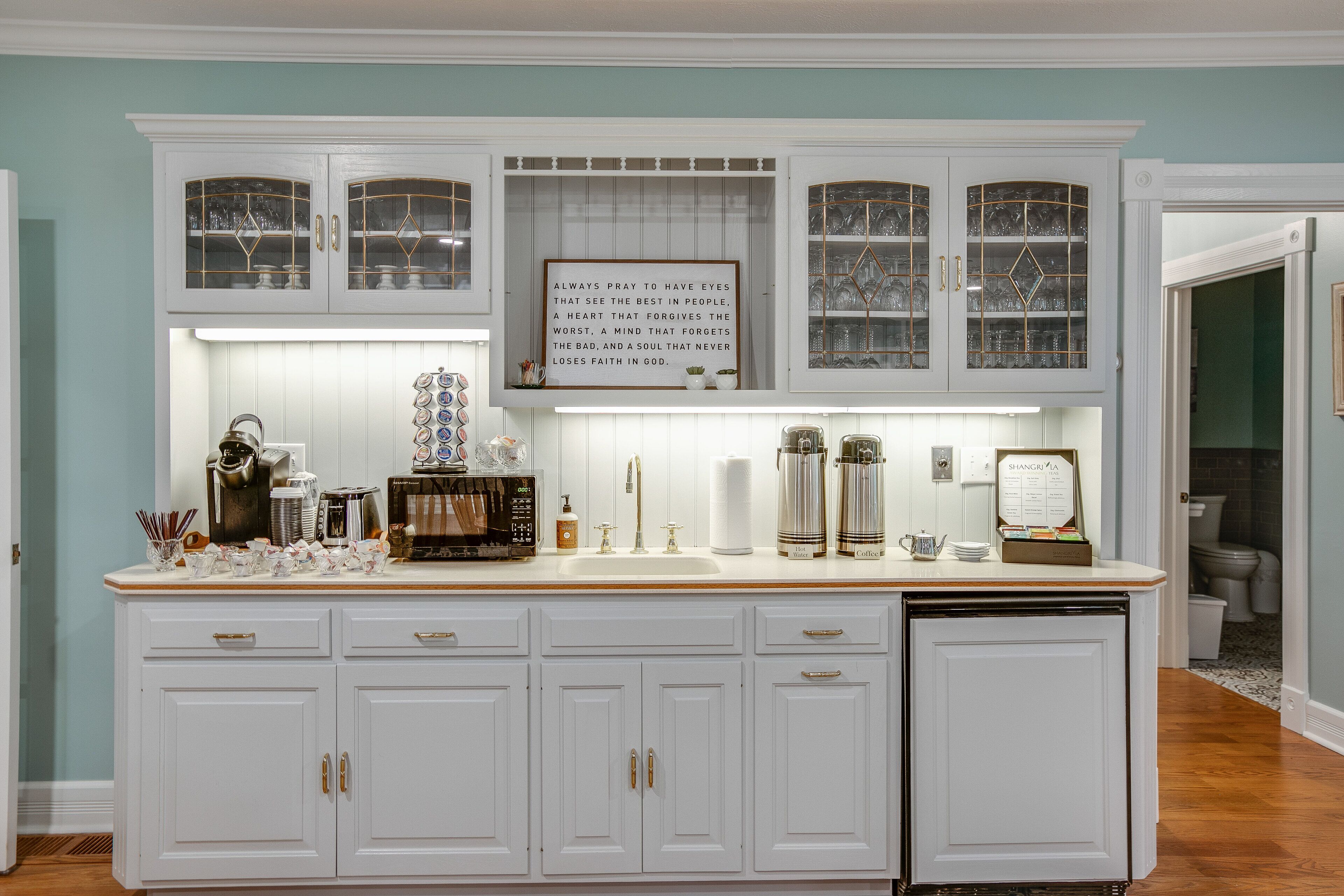 A kitchen with white cabinetry, a built-in microwave, and a coffee maker.