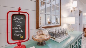 Un coin petit-déjeuner avec un tableau noir, une vitrine réfrigérée remplie de pâtisseries et un plateau de bouteilles.