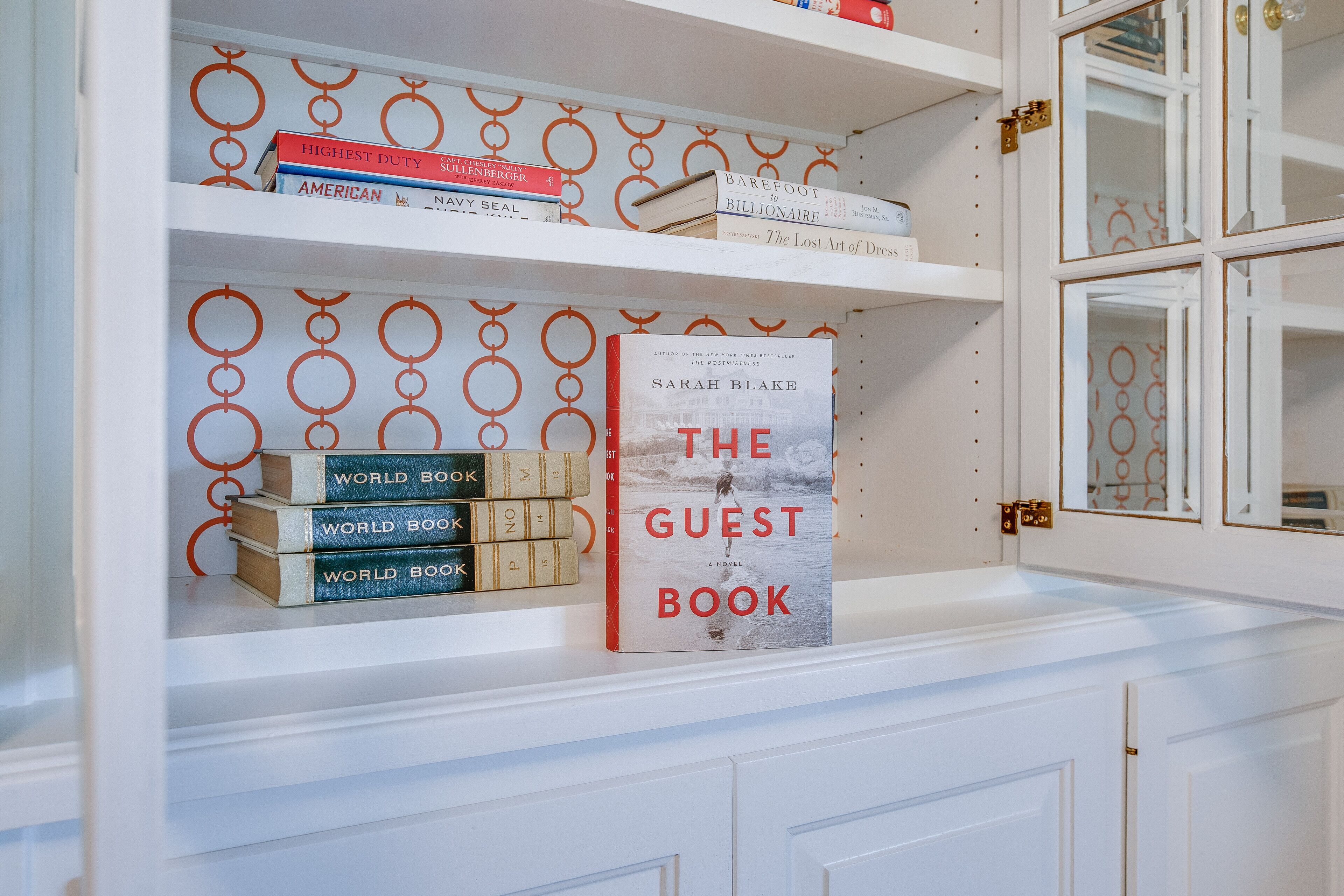 A bookshelf with books and a decorative pattern on the wall.