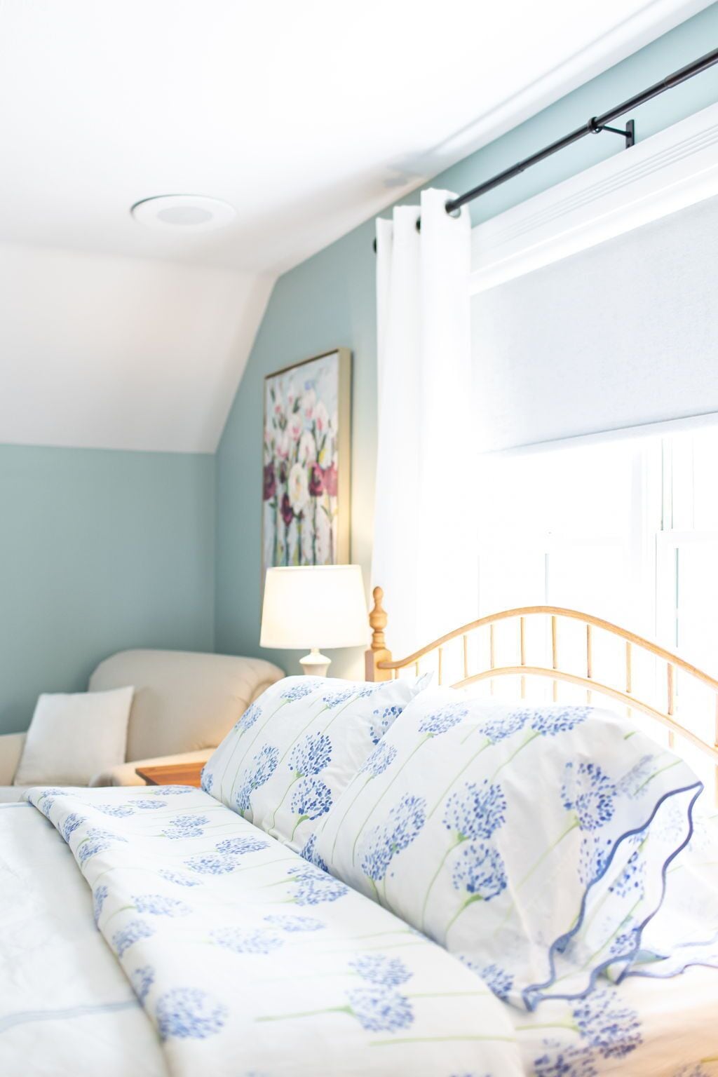 Un dormitorio con una cama, una mesita de noche, una lámpara y una ventana con cortinas.