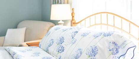 Un dormitorio con una cama, una mesita de noche, una lámpara y una ventana con cortinas.