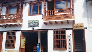 A two-story building with a sign for "Villa Pollos" restaurant. - Hospedaje Villa Monica (Villa de Leyva)