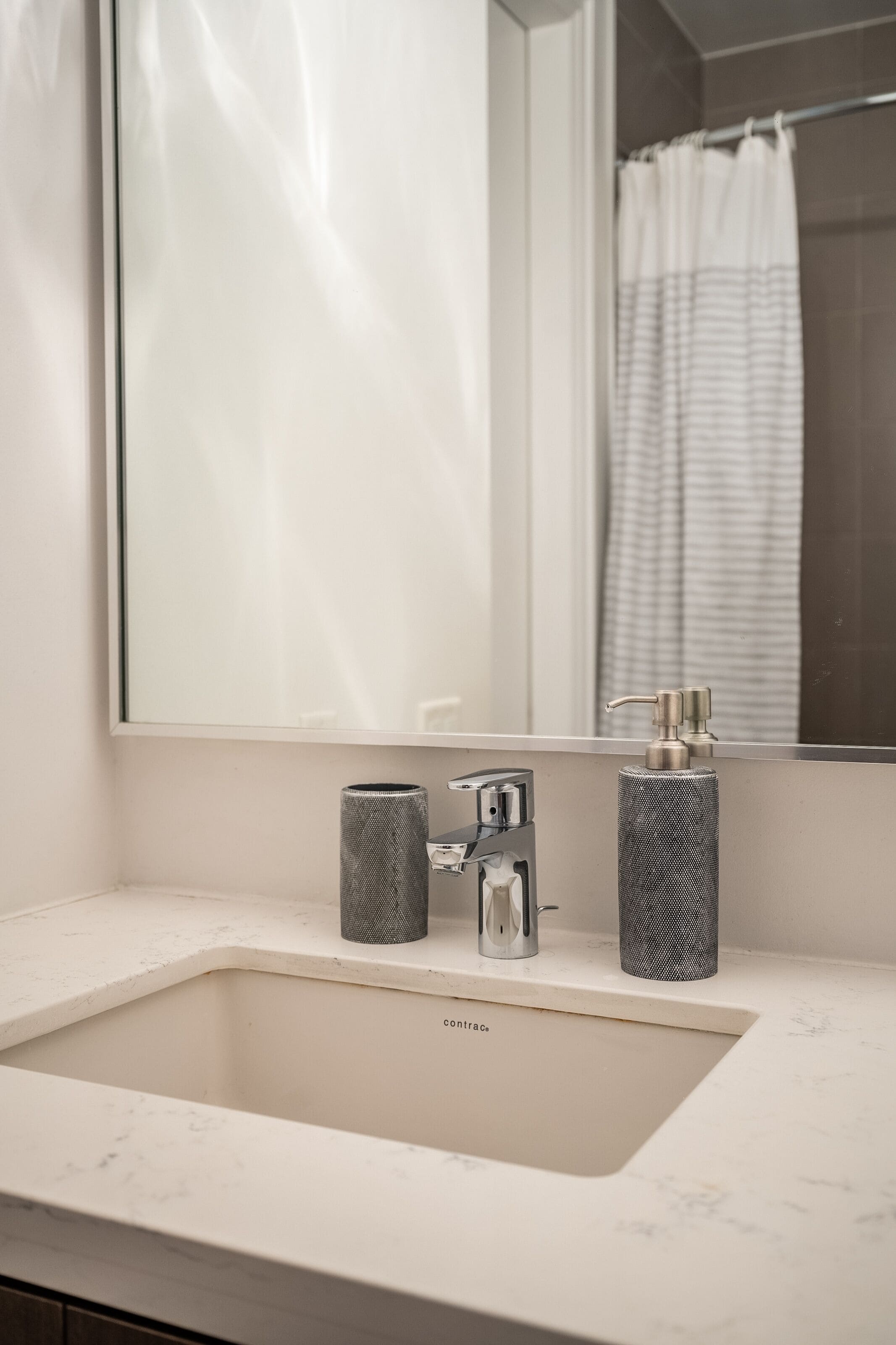 A bathroom with a white sink, a mirror, and a shower curtain.