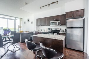 Una cocina moderna con armarios de madera oscura, electrodomésticos de acero inoxidable y una mesa de comedor de vidrio con taburetes de bar.