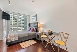 A bedroom with a bed, bedside table, lamp, and two chairs.